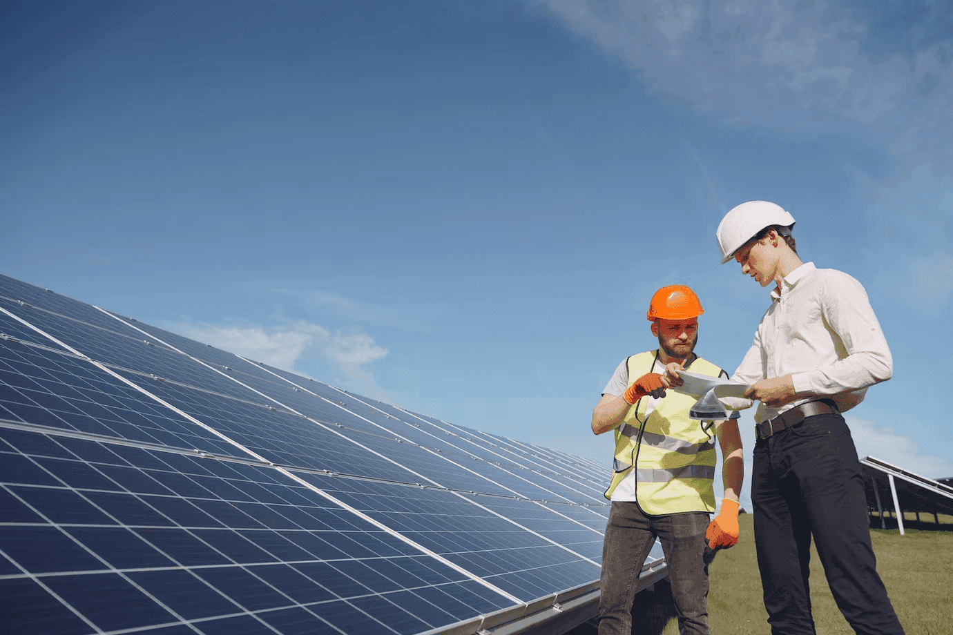 two technicians standing beside solar panels